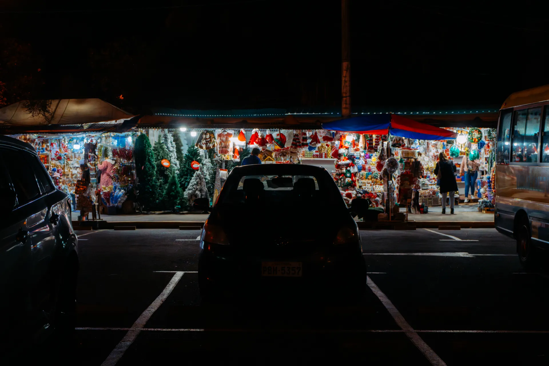 Carros y buses estacionados frente a los puestos de Navidad en Quito