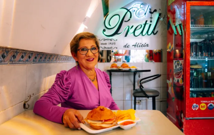 Alicia dentro de su local con el sánduche de pernil.