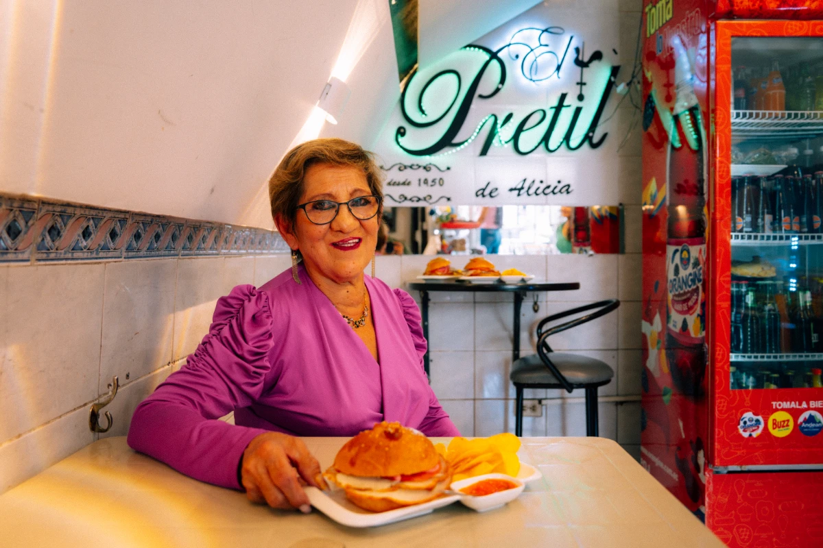 Alicia dentro de su local con el sánduche de pernil.